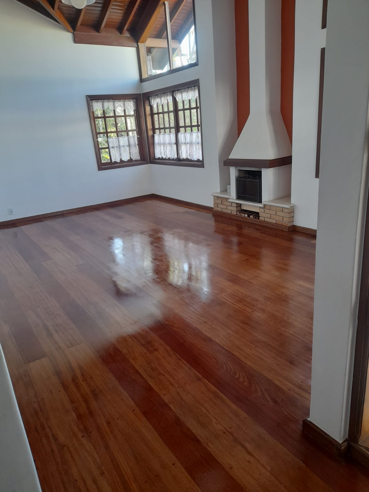 Sala com lareira e assoalho de madeira envernizado em Campinas