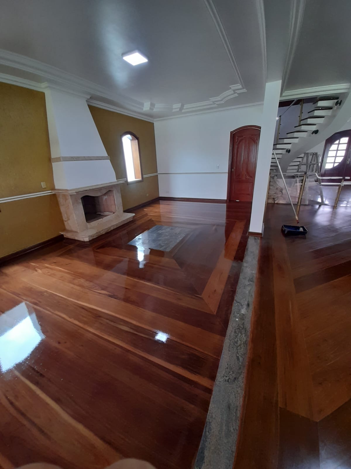 Sala com lareira e assoalho com detalhes em madeira após raspagem em Campinas