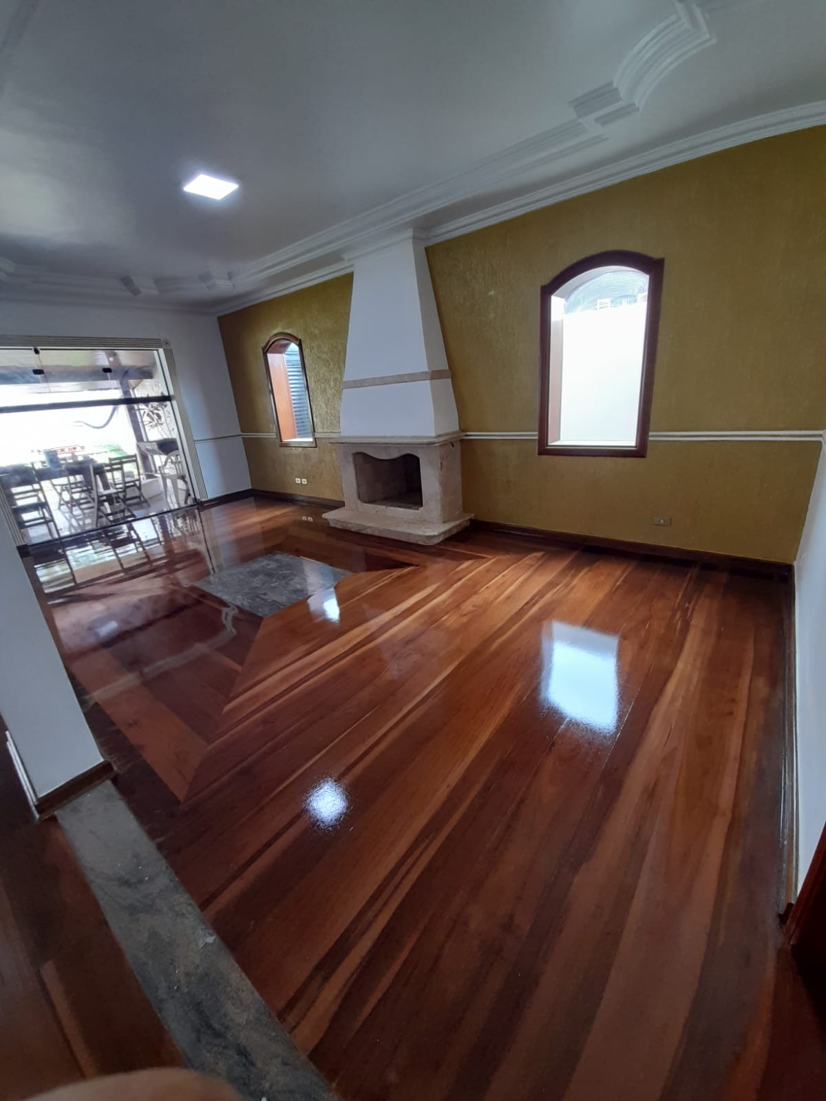 Sala com assoalho de madeira com desenho geométrico envernizado em Campinas