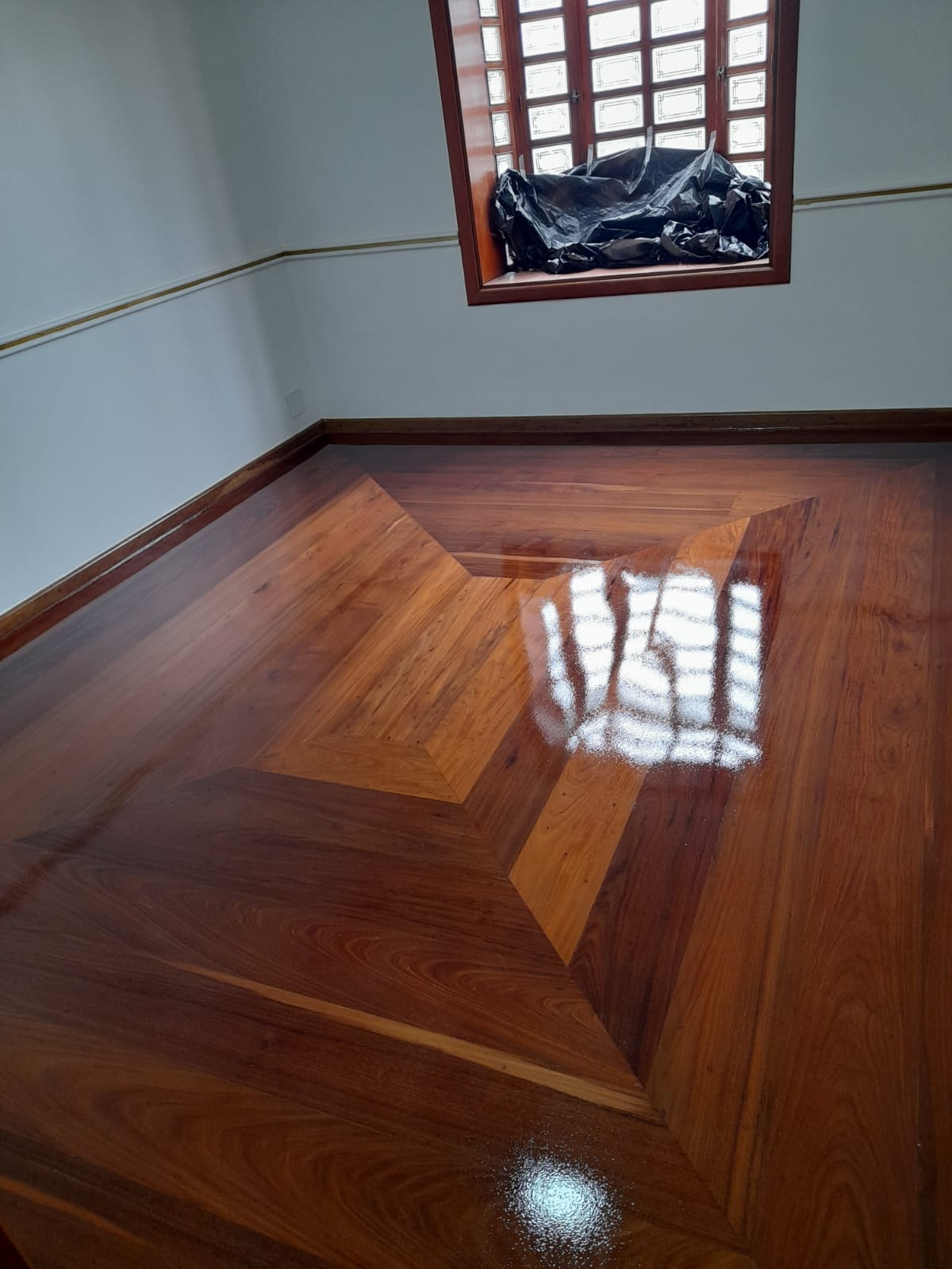 Piso de madeira com marchetaria em losango e verniz alto brilho em Campinas